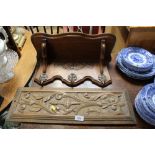 A carved wooden wall plaque; a wall shelf together with tree brass coat hooks