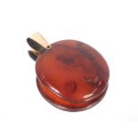 A large circular amber pendant with yellow metal ring fitting