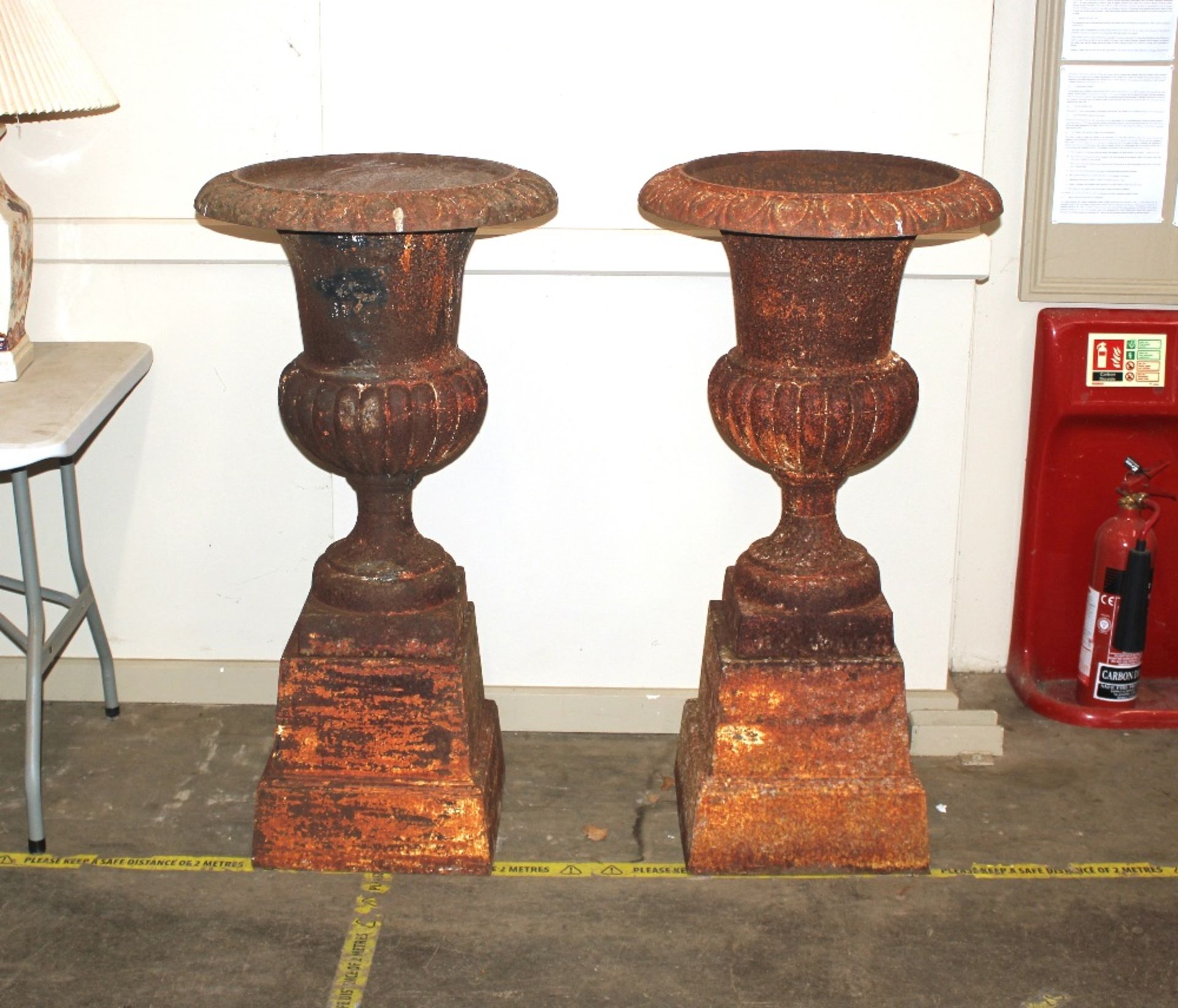 A pair of antique cast iron Campana shaped garden urns, of large size raised on separate stepped