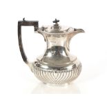 An Edwardian silver teapot with half fluted body decoration, black wood handle and lift; and a