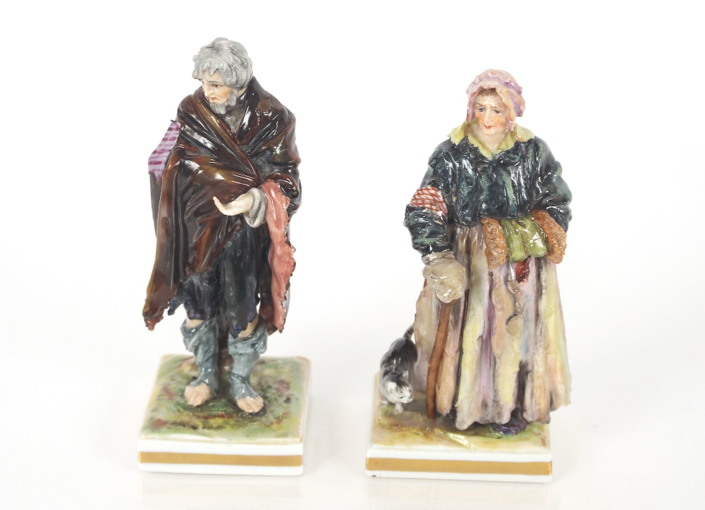 A pair of 19th Century Italian Naples porcelain figures of paupers wearing tattered clothes on