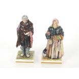 A pair of 19th Century Italian Naples porcelain figures of paupers wearing tattered clothes on