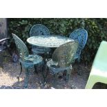 A cast metal garden table and four matching chairs