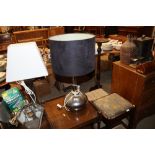 A table lamp and silvered base and dark shade