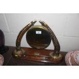 An antique brass dinner gong on horn supports, com