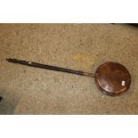 An antique copper warming pan with turned wooden h