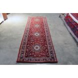An approx. 9'10" x 3'2" red patterned rug