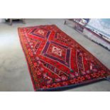 An approx. 11' x 5'5" red patterned rug