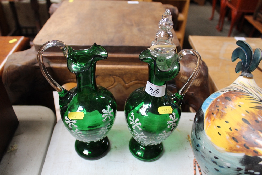 A pair of green glass and floral decorated decante