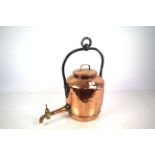 A large hanging copper kettle with brass tap and i