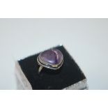 A white metal ring set with amethyst coloured ston
