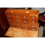 A bank of sixteen wooden filing drawers