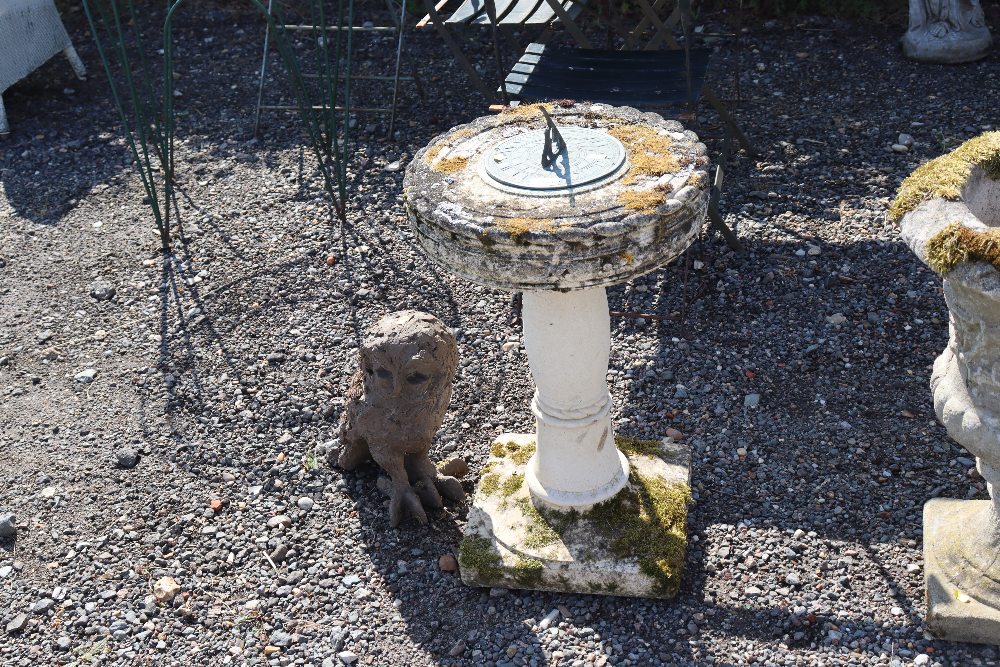 A sundial on concrete stand together with an owl ornament