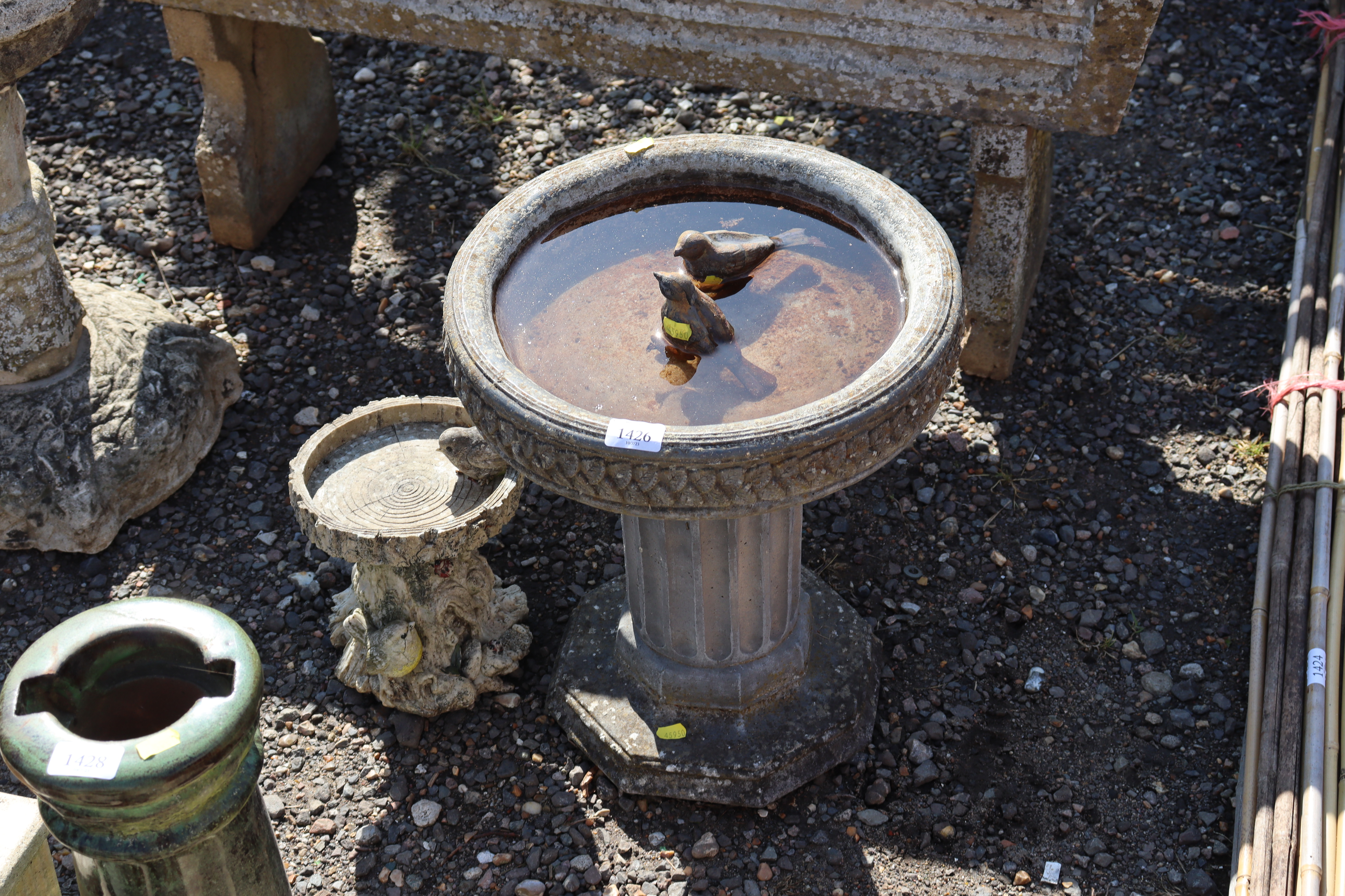 A concrete bird bath raised on plinth together wit