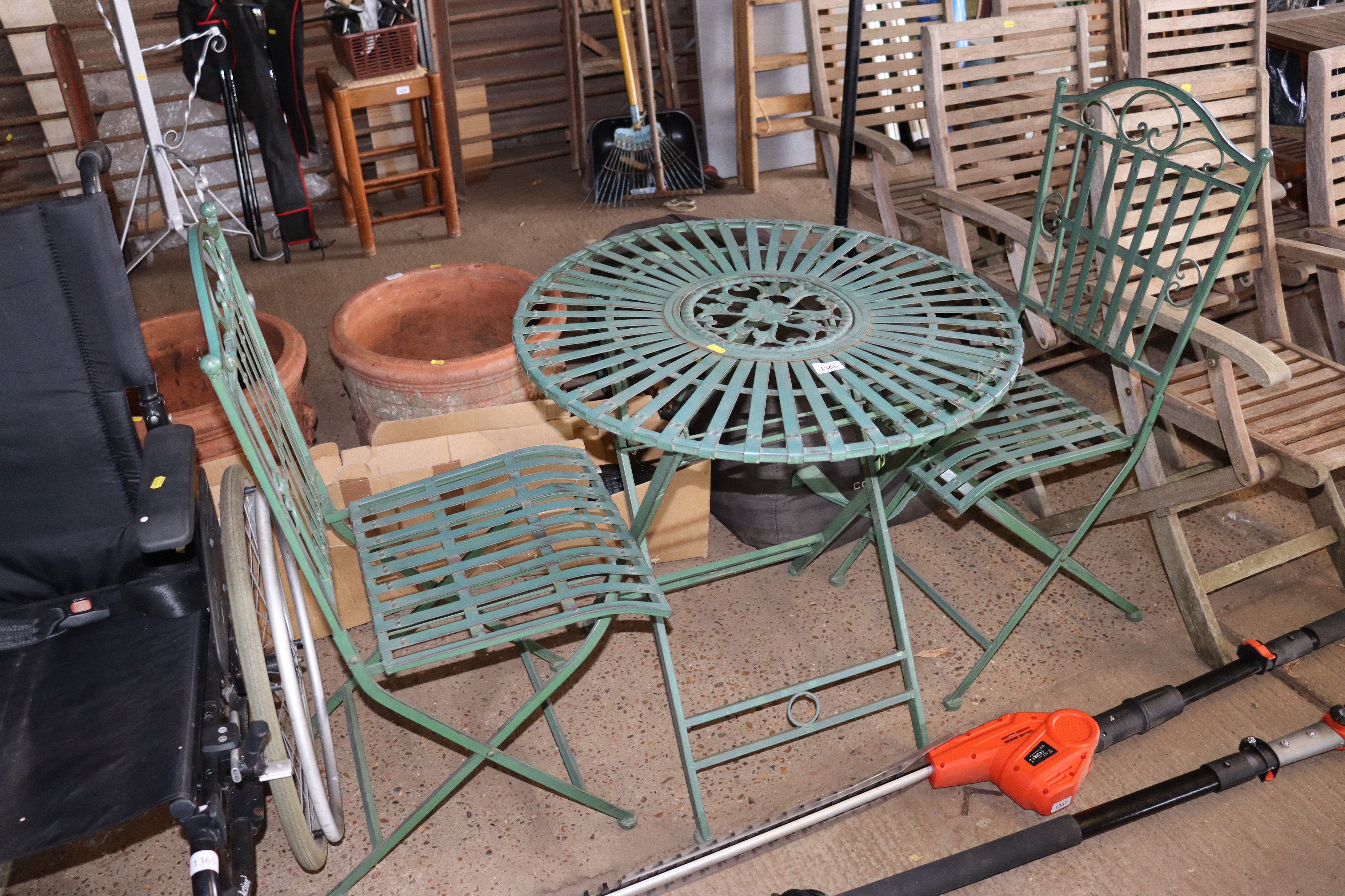 An ornate metal folding garden table and two match