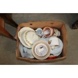 A box containing various patterned dinnerware; orn