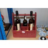 A wooden bottle carrier and five various bottle of