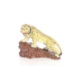 An early 20th Century Oriental porcelain /pottery model of a tiger standing on a rocky outcrop