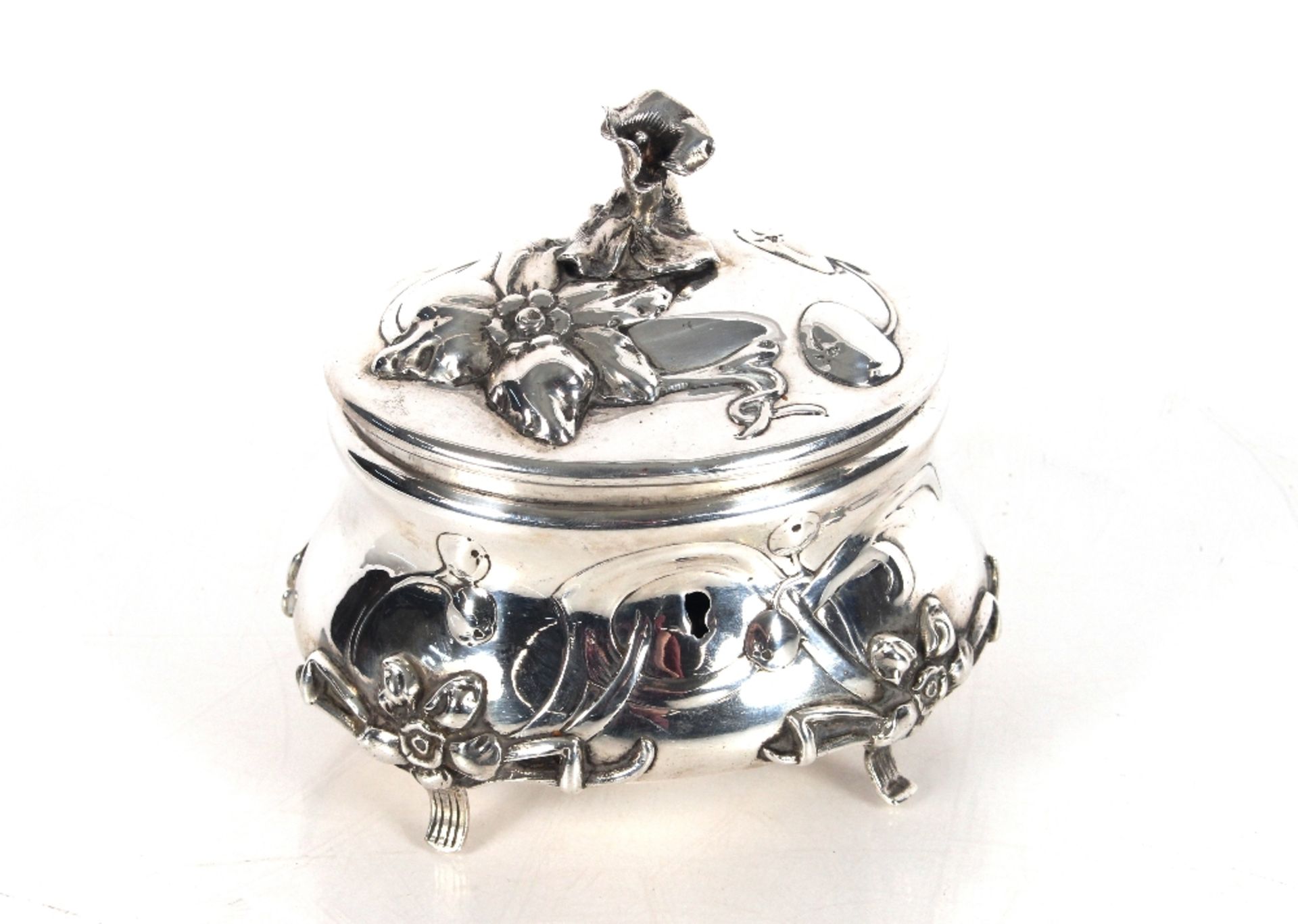 A continental white metal hinged casket, the lid surmounted by a flower finial, raised foliate heads