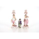 A pair of 19th Century German porcelain figural candlesticks, in the form of a maid and youth