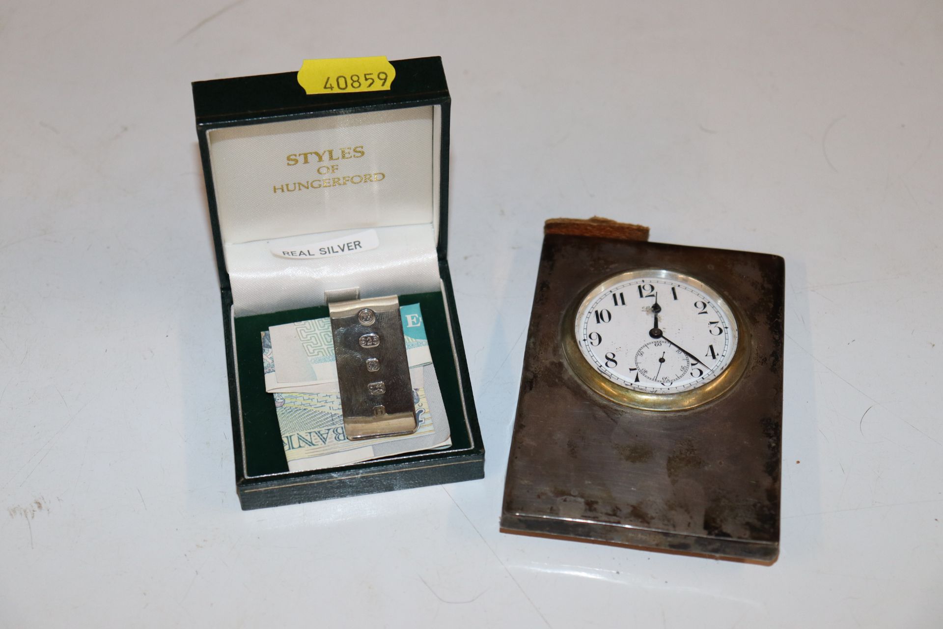 A silver cased travelling clock and a silver money