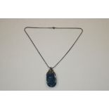 A polished blue stone and white metal pendant, hun