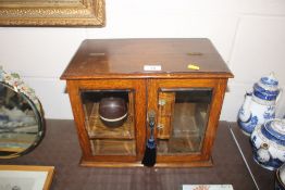 An oak and glazed smokers cabinet containing a Bak