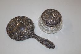 A silver hand mirror and silver topped jar