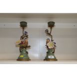 A pair of brass and porcelain candlesticks decorat