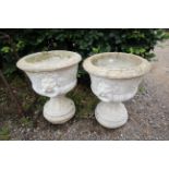 A pair of concrete garden urns with lion head deco