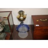 A brass and cast iron oil lamp with blue tinted sh