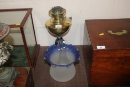 A brass and cast iron oil lamp with blue tinted sh