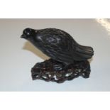 An Oriental carved Obsidian type bird on hardwood