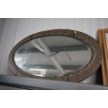 A copper framed oval and bevel edged wall mirror