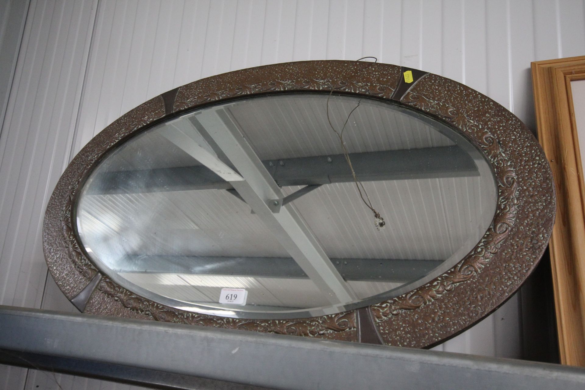 A copper framed oval and bevel edged wall mirror