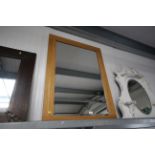 A light oak and bevel edged oblong wall mirror