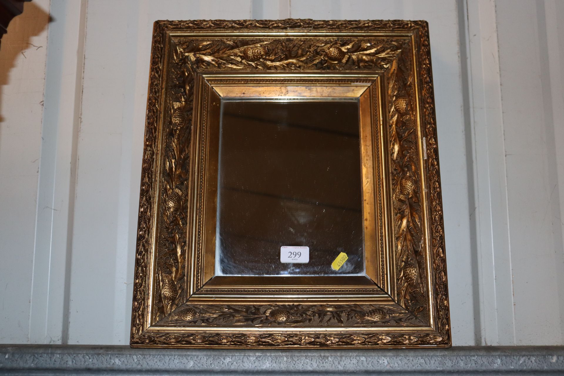 A gilt framed wall mirror with floral decoration