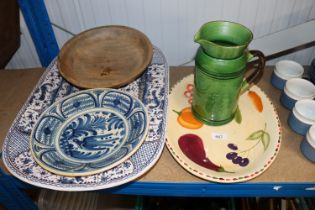 A large serving plate; green glazed jug; wooden bo