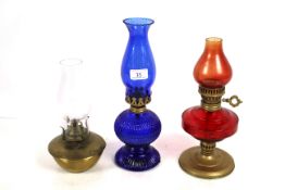 Two red and blue glass oil lamps and a small brass
