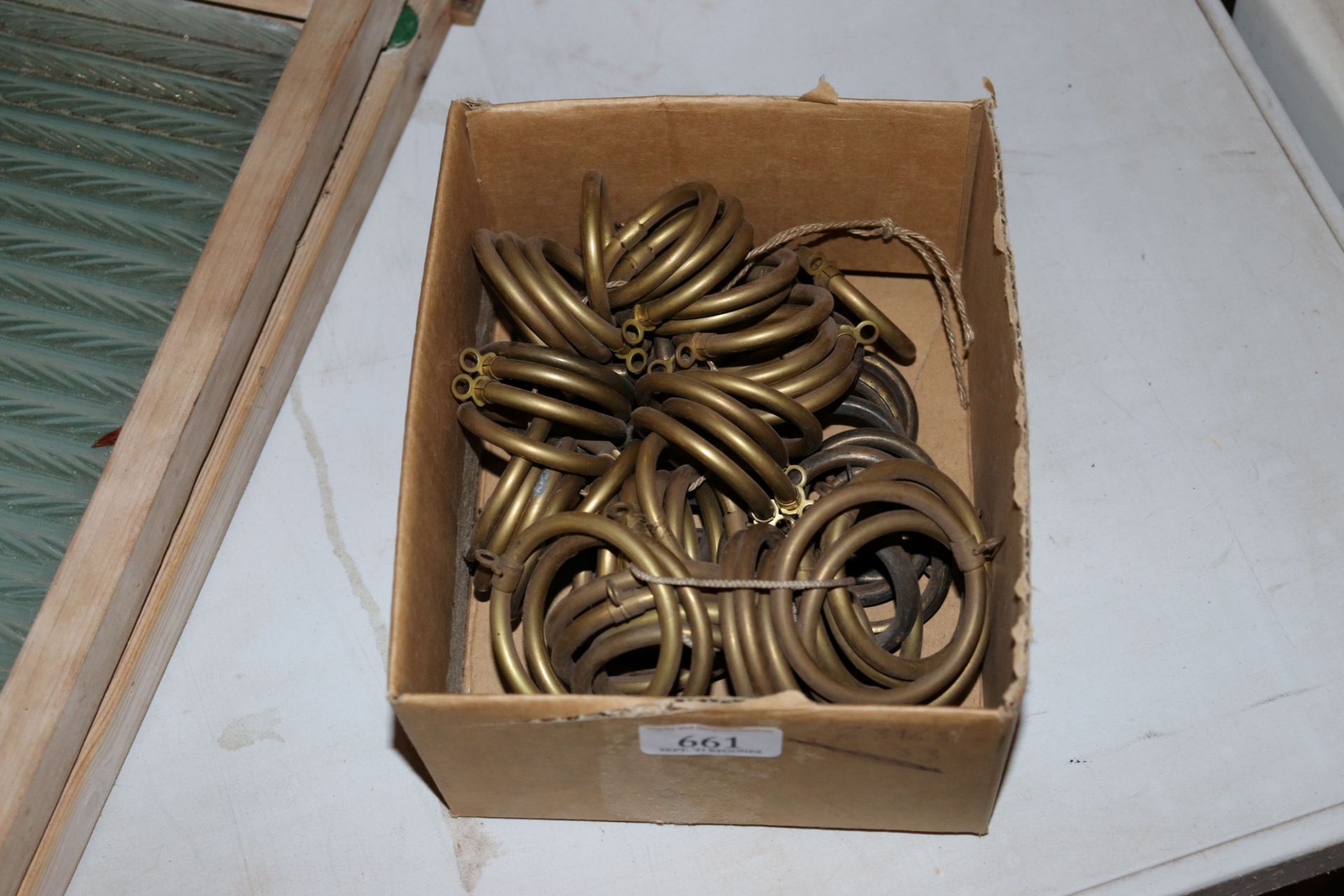 A box containing miscellaneous brass curtain rings