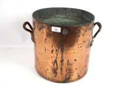 A large antique copper twin handled cooking pot