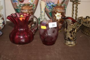 A cranberry glass jug with gilt mount; an etched c