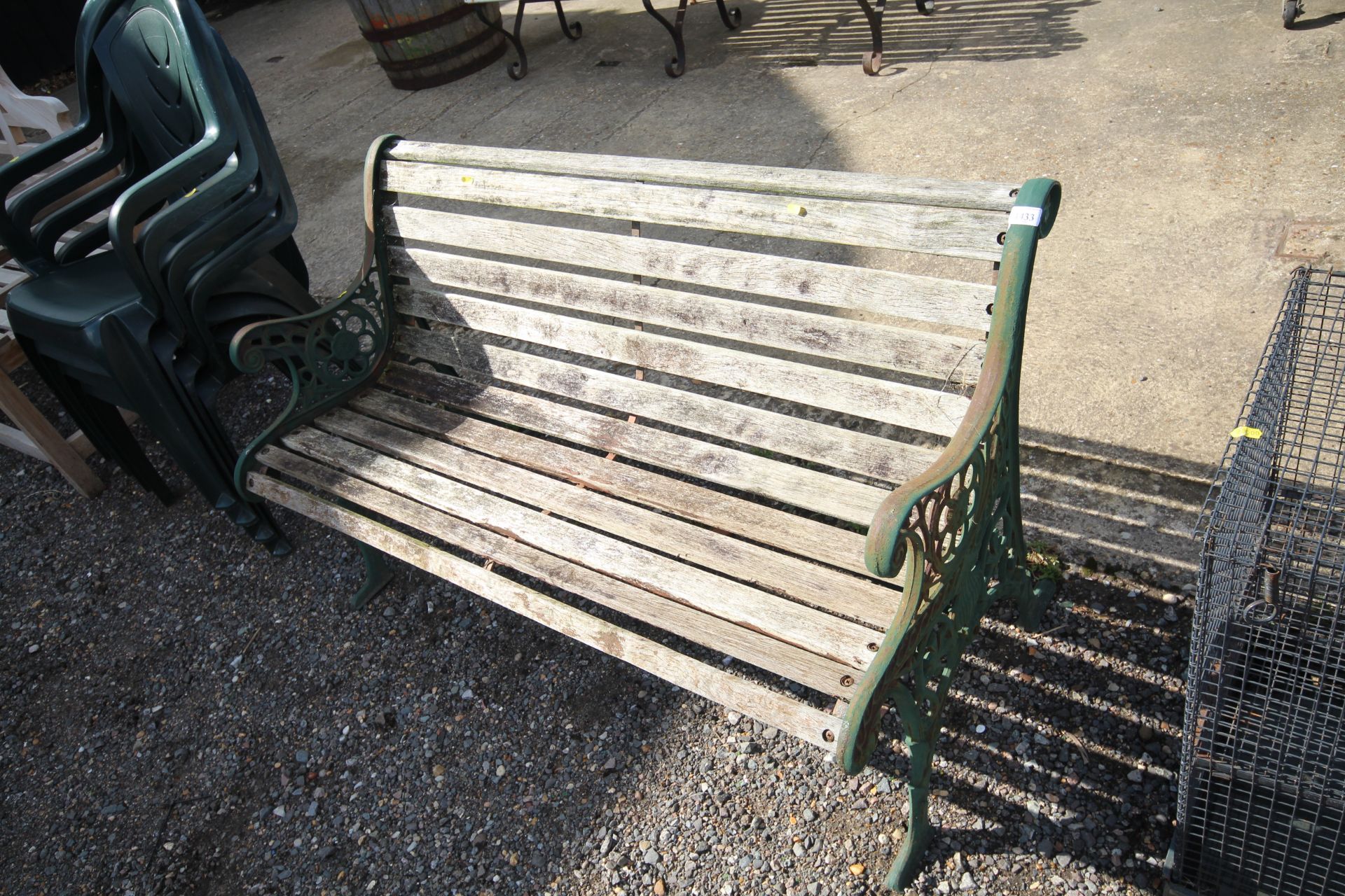 A two seater wooden slatted garden bench with gree