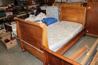 A sleigh type bed lacking slats with mattress