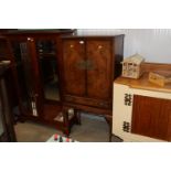 A walnut veneered drinks cabinet raised on cabriol