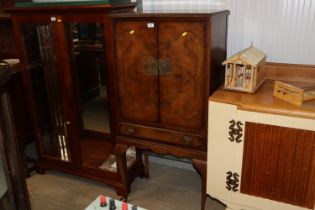 A walnut veneered drinks cabinet raised on cabriol