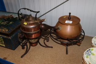 A decorative copper kettle on wrought iron spirit heater stand and a copper fondue saucepan with