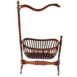 A mahogany rocking baby cradle, surmounted by a carved dragon head with ring turned decorated