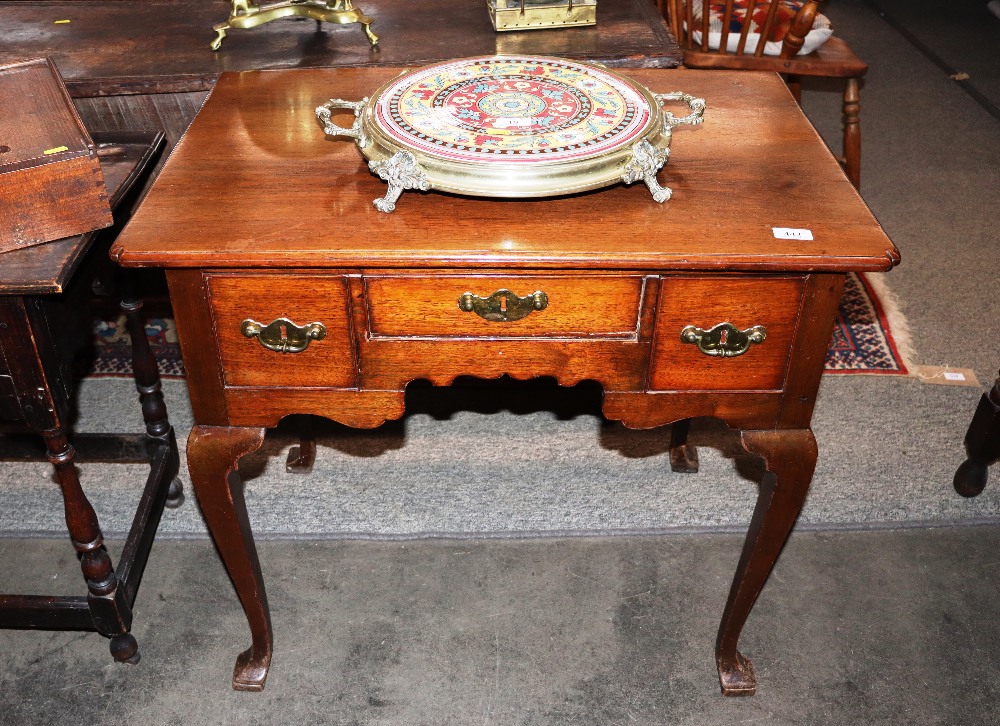 An antique mahogany low boy, the shaped top above three drawers and arched frieze, raised on