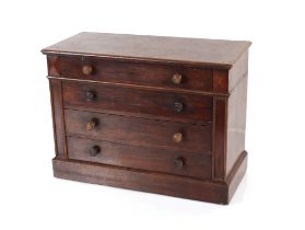 A mahogany table top four drawer miniature cabinet, fitted turned handles and raised on a platform